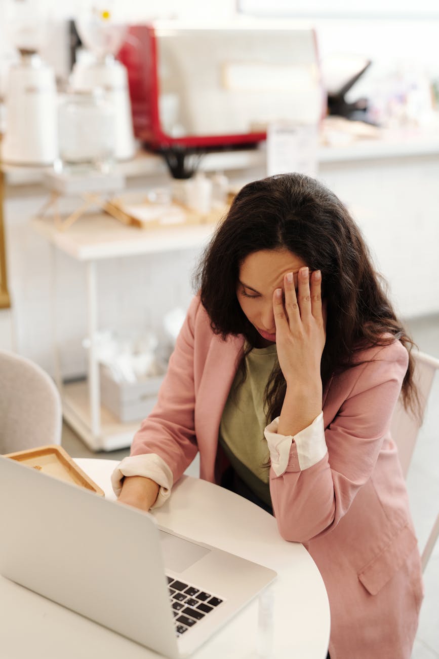 a woman looking sick while working with her laptop